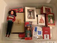 Photo of loose Barbie doll and boxed Barbie and Kelly Club Christmas ornaments inside a plastic storage container.