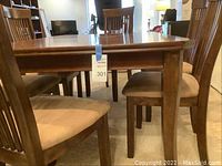 Full view of the dark wood dining table with four chairs around it, showing the table surface, legs and chair backs.