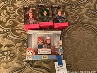 Photo of four boxed dolls: two Tommy dolls, one Kelly doll, and one Barbie Raggedy Ann & Andy set.