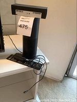 Amazon Echo smart speaker placed on a white surface, with power adapter and remote box on top.