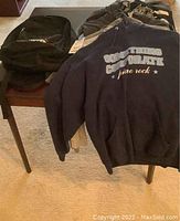Photo showing assorted ladies sweatshirts and a backpack on a wood table.