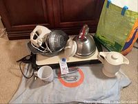 Photo showing the entire lot including the hand mixer, tea kettle, griddle, bakeware, and teapot together on a cloth.