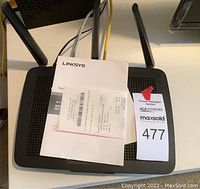Top view of the Linksys router with four antennas and documents including receipt and warranty placed on top.