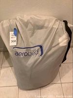 Gray carrying bag with Coleman Aerobed logo, containing queen size air mattress.