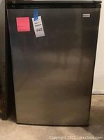 Front view of the small Kenmore refrigerator showing stainless steel door with black handle and top edges.