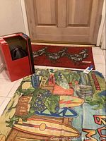 Photo of Bell bike helmet in box, chicken-themed rug, and colorful beach towel on floor