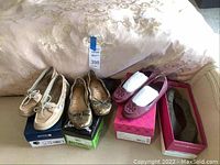 Three pairs of women's flats displayed on a bed with shoe boxes, showing overall condition and styles