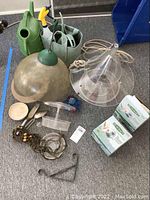 Lot items including two boxed bird feeders, three green watering cans, tote with dirt, metal chains, and other small accessories all needing cleaning, some with damage.