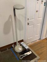 Full view of Verilux lamp with flexible neck and base, showing accompanying cords and plugs on floor.
