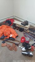 View showing orange Lands End down jacket, red vest, several pairs of men's shoes including brown leather and casual, and slippers on carpet floor.
