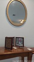 Three panel folding mirror set with beveled glass, wood frames, and decorative tooled side panels resting on wood furniture