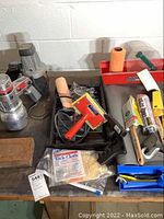 Image showing assortment of paint supplies including paint rollers, brushes, tack cloth, a red paint tray, and small painting accessories.