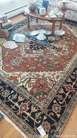 Full view of the large geometric and Southwestern style rug showing colors, central pattern, and surrounding objects for scale.