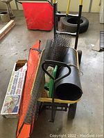 Overview of wagon loaded with chicken wire, gutter guard, leaf grabbers, and orange leaf haulers on concrete floor