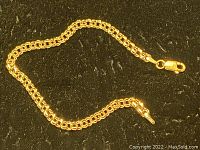 Full view of gold chain bracelet on black background