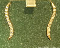 Front view of the pair of curved earrings with rhinestones lined up along the front, gold metal visible at the tips and ends.