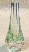 Front angle of clear blown glass bud vase showing blue vertical rods and green swirl pattern inside