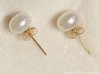 Pair of cultured pearl stud earrings shown from above on white background to display pearls and gold posts.