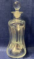 Front view of clear crystal decanter showing sculpted vertical ridges and round stopper.