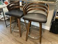 Front view of two walnut finish bar stools beneath counter