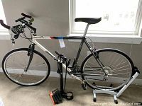 Full side view of bicycle mounted on stand with pump and coiled lock on handlebars