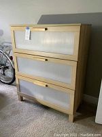 Front angle view of the wood look dresser showing three drawers with translucent ribbed plastic panel inserts and horizontal wood handles.