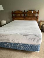 Full view of the mattress on box spring with partial frame and headboard visible in bedroom setting.