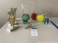 Full set of items arranged on table including blown glass fish, vases, and trophies