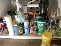 Overview photo showing kitchen cleaning products under sink including sprays, wipes, brushes, and liquid soaps.