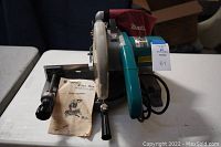 Front and top view of the Makita miter saw with instruction manual and handle.
