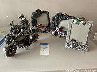 Photo of four motorcycle-themed picture frames and two metal motorcycle sculptures arranged on a table