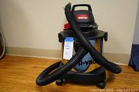 Full view of Shop Vac with metal canister and attached flexible hose.