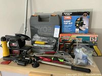 Wide photo showing all tools laid out on table with Ryobi drill case, Sears belt sander, Black & Decker Sand Storm sander, flashlight, clamps, safety goggles, Ramp Top Kit box