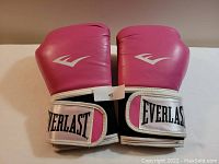 Front view of pink Everlast boxing gloves with logo on wrist strap.