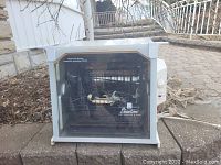 Showtime Rotisserie BBQ oven showing front with transparent door and visible rotisserie mechanism inside, placed outdoors.