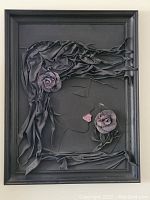 Photo of a framed leather wall art showing a woman's side profile with roses made of layered leather pieces in black and purple tones.
