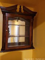 Wooden wall-mounted display cabinet with glass door and decorative top molding