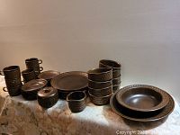 Full view of all tableware pieces arranged on a table showcasing cups, saucers, plates, bowls, creamer, sugar bowl, and serving plates.
