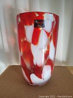 Full view of the tall glass vase showing the red and white mottled pattern.