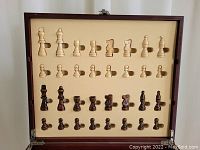 Chess set pieces organized in molded foam interior inside the wooden box lid, showing complete rows except some missing pieces.