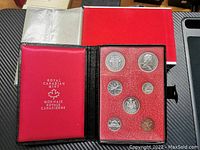Red presentation folder with seven coins displayed in clear slots, labeled Royal Canadian Mint.