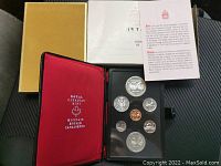 Full view of the coin set housed in a black case with clear cover, red interior lid with Royal Canadian Mint branding, and outer box and certificate.