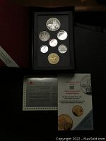 Full view of the 1990 Canadian proof coin set in a black display case with accompanying commemorative literature booklet showing the special edition silver dollar and six circulating coins.