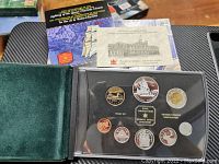 Opened black presentation case with 8 Canadian coins in proof condition and a special edition silver dollar coin from 1999