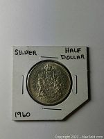 Obverse side of 1960 Canadian silver 50 cent coin displaying the detailed coat of arms and year 1960, mounted in holder labeled silver half dollar.