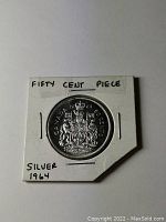 Front side of the 1964 Canadian silver 50 cent coin showing the Canadian coat of arms and markings.