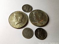 Front view of 5 silver coins showing dates and designs