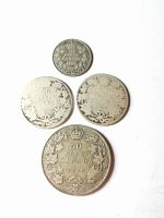 Top view of four Canadian silver coins arranged on white background showing 1920 50 cents coin and three smaller coins with maple leaf design.