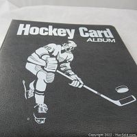 Front cover of black vinyl binder with white “Hockey Card Album” text and player graphic.