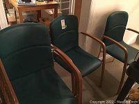 Set of four Mid-Century Modern style chairs in green upholstery with wood arms and metal frames grouped together.